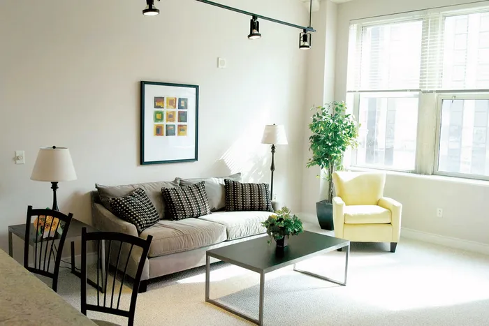 Bright and cozy living room featuring a plush gray sofa, chic coffee table, and a sunny yellow armchair by a large window, adorned with modern decor.