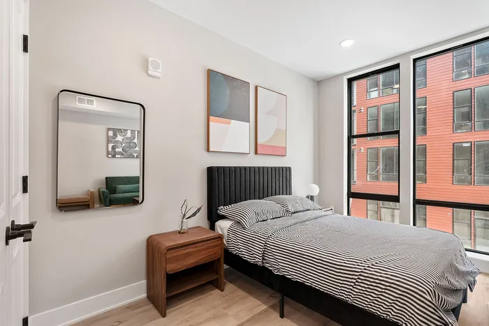 Bright and modern bedroom with chic decor, stylish striped bedding, and large windows offering abundant natural light.