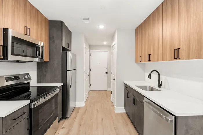 Sleek modern kitchen with stainless steel appliances, elegant wood cabinetry, and polished countertops, offering a chic and functional space.