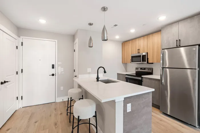 Contemporary kitchen with sleek stainless steel appliances, pendant lighting, and a modern breakfast bar with comfy stools.