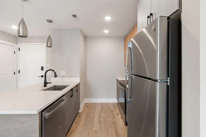 Modern kitchen with sleek stainless steel appliances, stylish pendant lighting, and elegant white countertops.