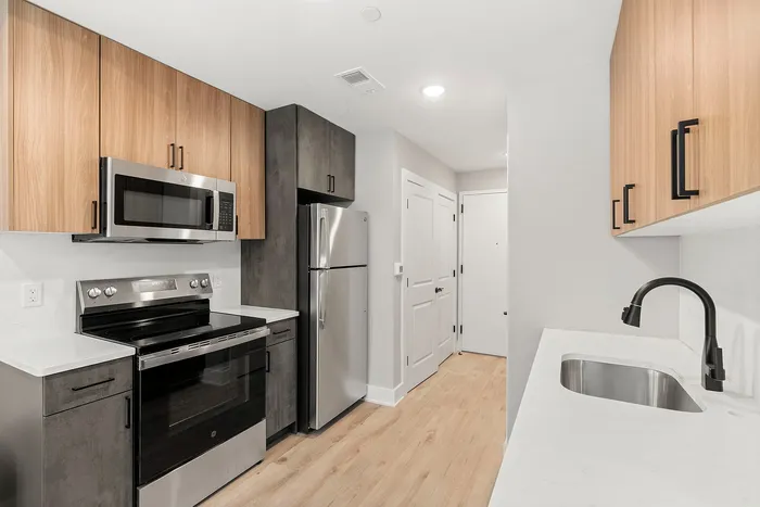 Modern kitchen with sleek stainless steel appliances, elegant wood cabinetry, and stylish black fixtures.