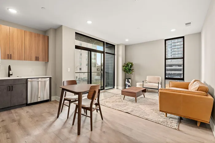 Modern open-plan living area with sleek kitchen, stylish dining set, and elegant seating, featuring natural light and contemporary decor.