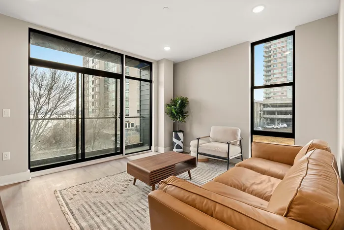 Chic apartment living area with floor-to-ceiling windows, modern leather couch, and serene city view.