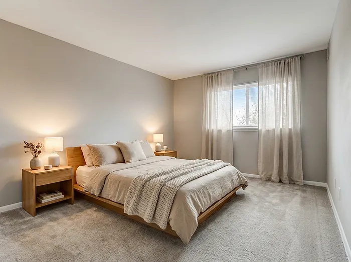 Elegant bedroom with a cozy atmosphere featuring a plush bed, soft lighting, and a large window with sheer curtains.