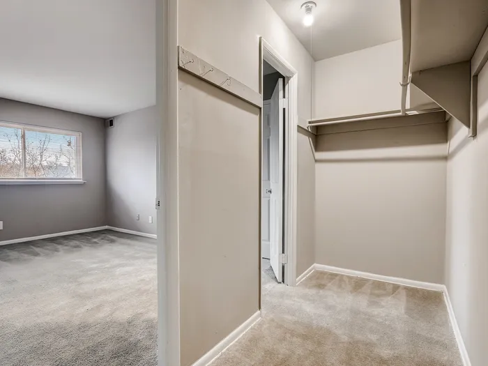 Inviting bedroom with natural light and a spacious, well-organized walk-in closet.
