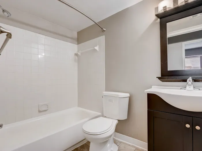 Elegant apartment bathroom featuring modern fixtures, sleek vanity, and pristine white bathtub.