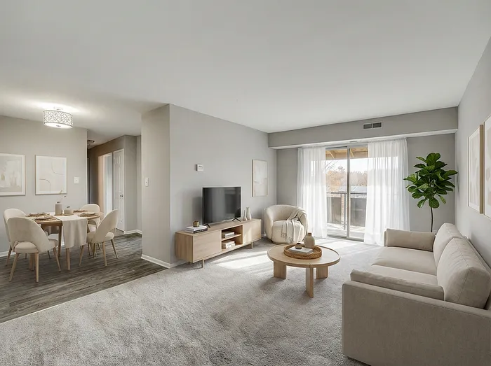 Inviting modern living room with comfortable beige sofa, flat-screen TV, and bright natural light from large windows opening to a balcony, adjacent to a stylish dining area with elegant chairs.