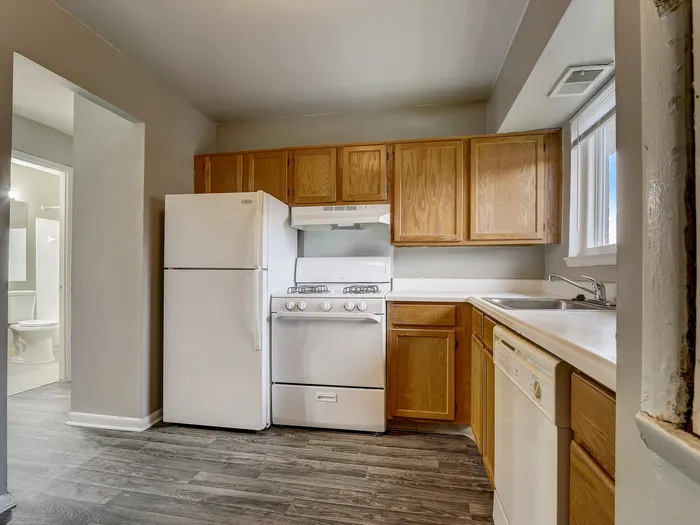 Charming kitchen with sleek white appliances, abundant wooden cabinetry, and modern flooring, perfect for culinary creativity.