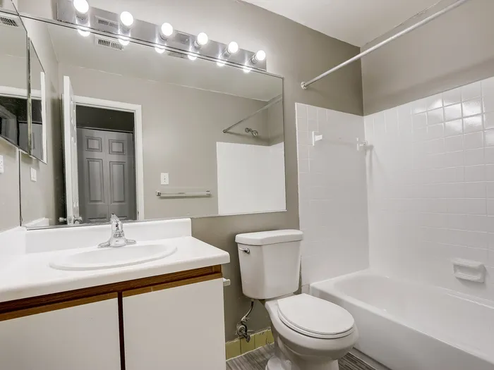Modern and bright bathroom featuring a sleek vanity, large mirror, and a chic subway tile bathtub.