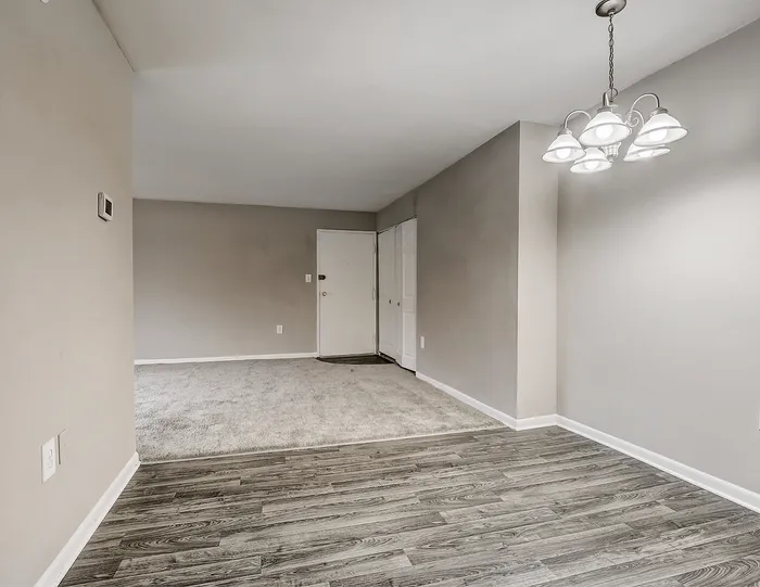 Modern apartment interior featuring sleek wooden floors, soft gray walls, and elegant overhead lighting in a spacious open-plan layout.