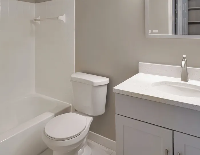 Modern bathroom showcasing elegant white fixtures, a spacious bathtub, sleek countertop, and stylish cabinetry for a luxurious feel.