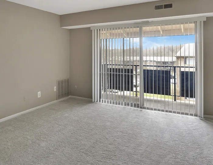 Bright and inviting empty room with large sliding doors opening to a sunlit balcony, perfect for enjoying morning views.