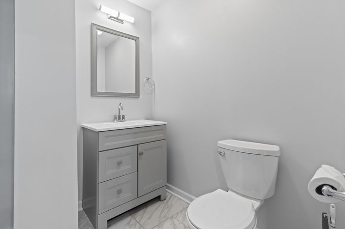 Modern bathroom featuring a sleek gray vanity with ample storage, complemented by a chic mirror and elegant marble flooring.