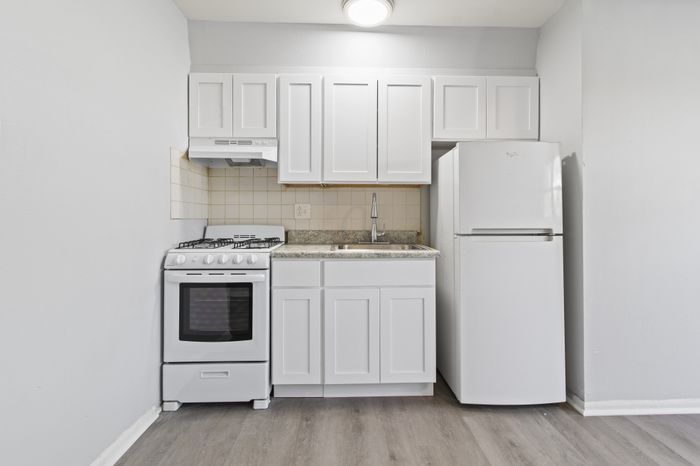 Chic compact kitchen featuring modern white cabinets, stainless steel sink, and sleek appliances for an efficient culinary space.