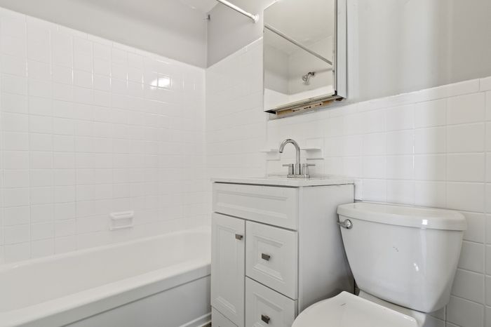 Bright, modern bathroom with sleek white tiles, chic vanity, and elegant fixtures.