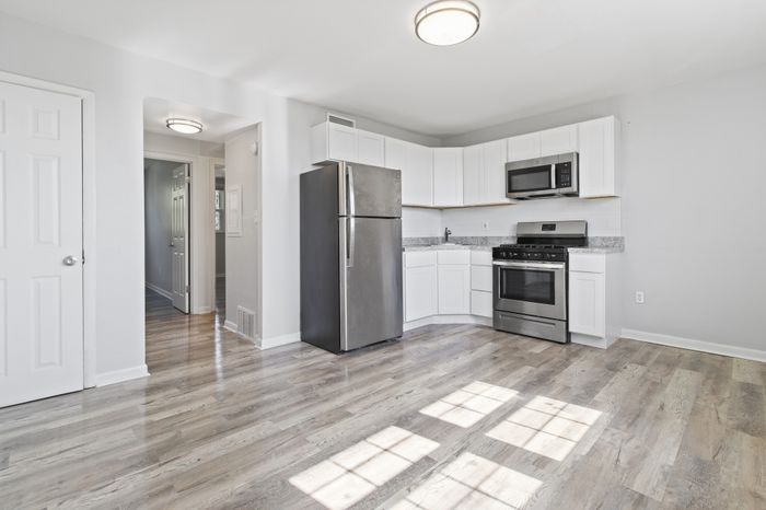 Bright, modern kitchen with sleek stainless steel appliances, elegant white cabinetry, and beautiful hardwood floors.