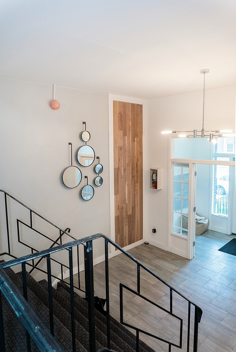 Elegant entryway featuring modern geometric mirrors, sleek lighting, and a welcoming staircase with stylish railing.