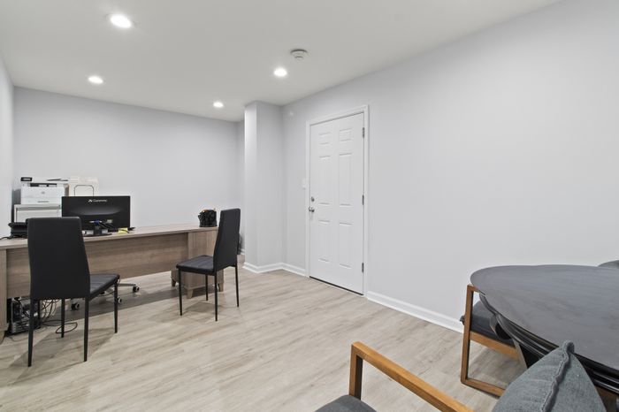 Modern office space with sleek desk and chairs, bright lighting, and minimalist decor.