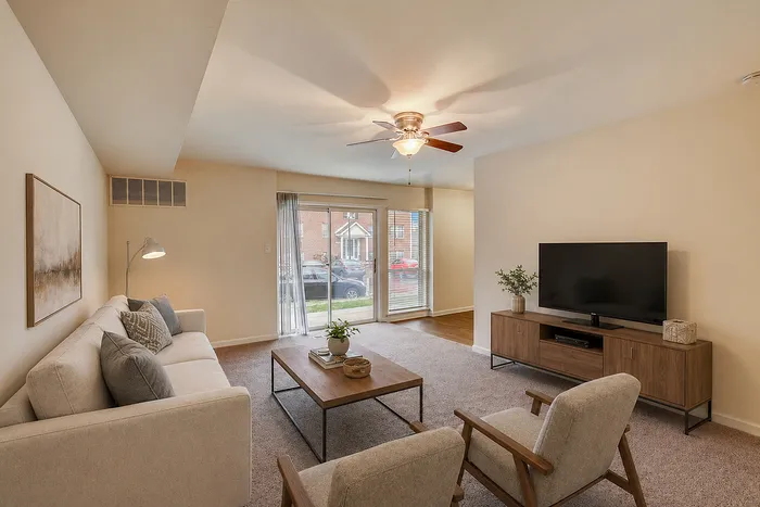Inviting living room with natural light, featuring a cozy beige sofa, modern coffee table, and sleek TV stand.