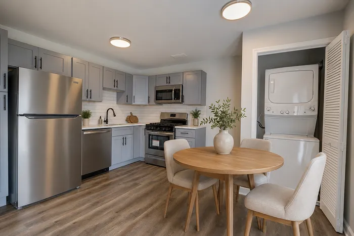 Modern kitchen with sleek stainless steel appliances, elegant gray cabinetry, and a cozy dining area, complete with in-unit washer and dryer for convenience.