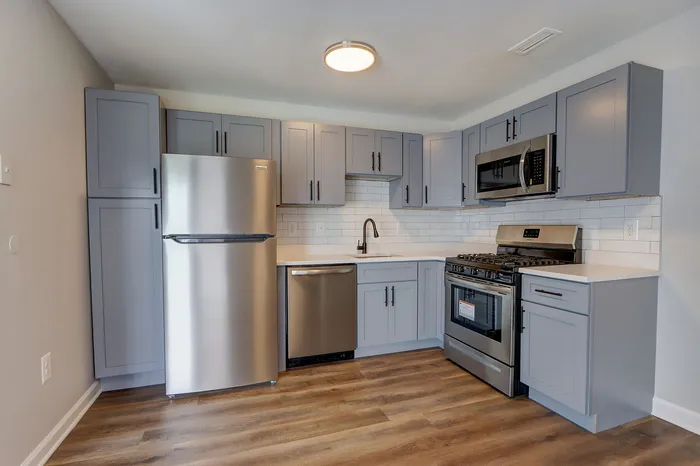 Modern kitchen with sleek gray cabinetry, stainless steel appliances, and gleaming hardwood flooring for a contemporary living space.