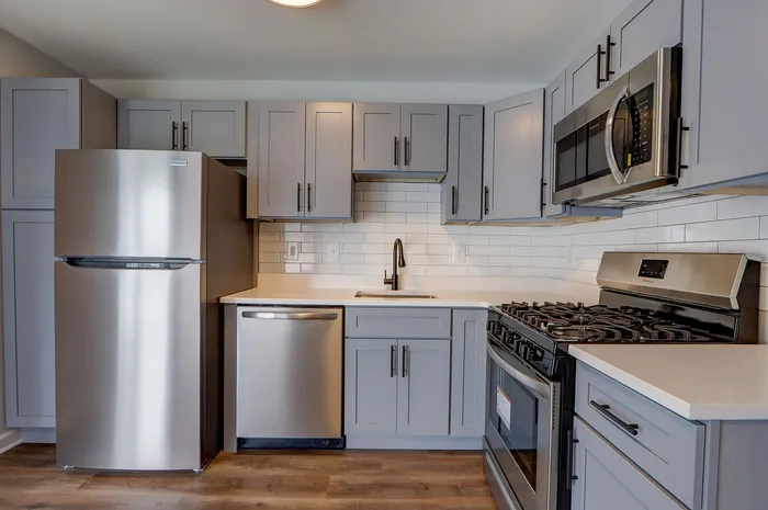 Contemporary kitchen with sleek grey cabinetry, stainless steel appliances, and elegant tile backsplash.