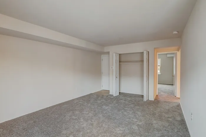 Spacious bedroom with plush carpeting, inviting neutral walls, and ample closet space, perfect for modern living.