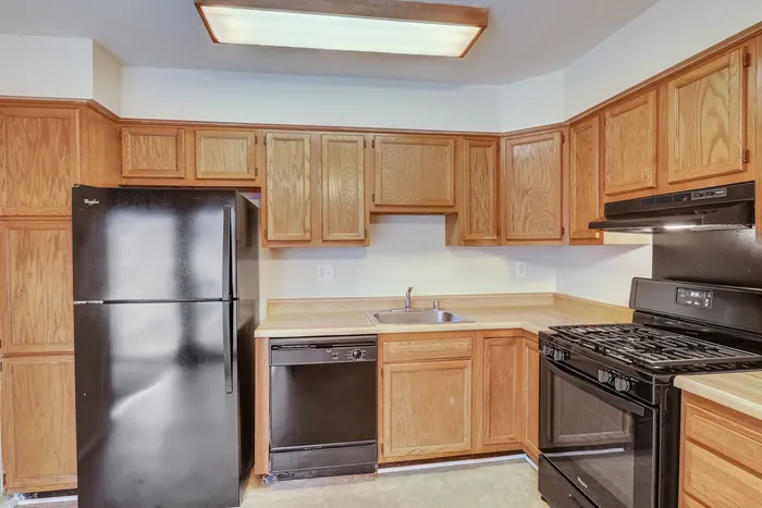 Inviting kitchen with sleek black appliances, warm wooden cabinets, and ample countertop space.