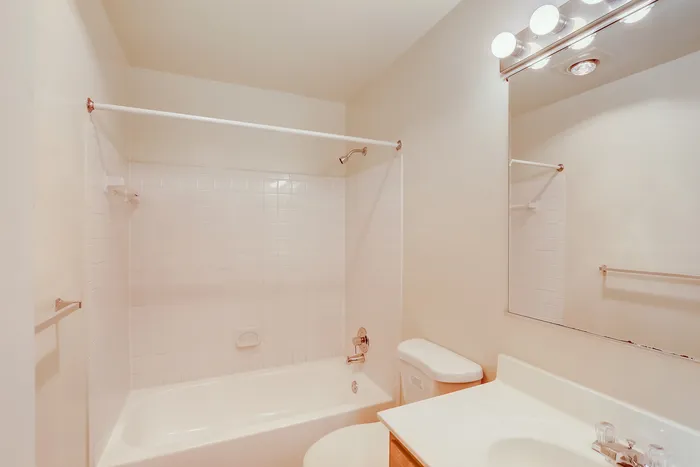 Bright and inviting bathroom with pristine white tiles, modern fixtures, and ample lighting.