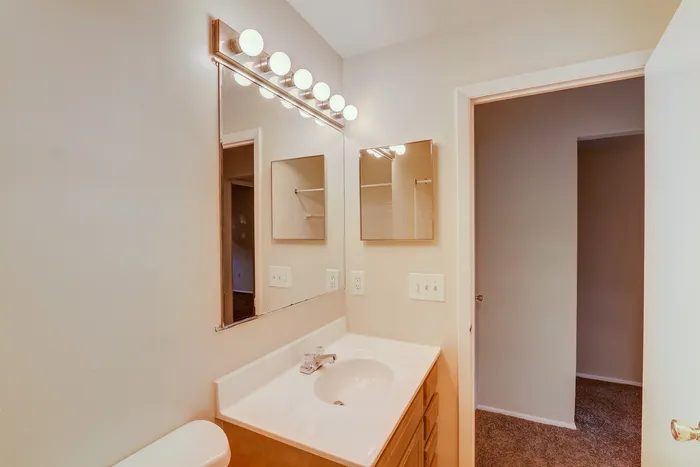 Bright and inviting bathroom with stylish vanity lighting, sleek countertop, and ample mirror space.