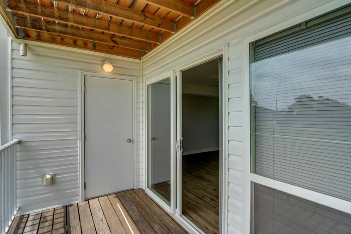 Charming balcony with wood deck and sliding glass doors, perfect for enjoying serene outdoor views.