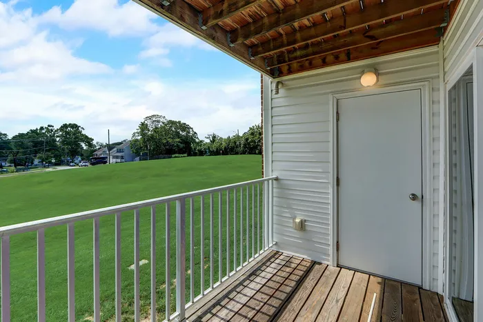 Inviting balcony view overlooking a lush green landscape, featuring a cozy outdoor space with warm wooden flooring.