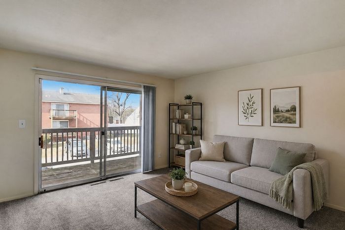 Bright and welcoming living room featuring a spacious sofa, tasteful decor, and large sliding glass doors opening to a serene balcony view.