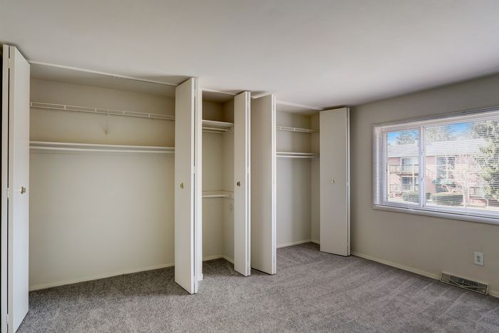 Expansive bedroom with ample closet space and natural light from a large window overlooking the neighborhood.