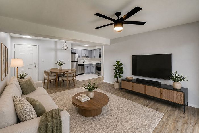 Modern open-concept living room with cozy beige sofa, elegant dining area, and sleek kitchen featuring stainless steel appliances.