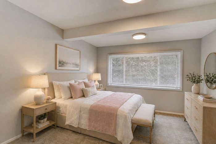 Elegant bedroom featuring soft lighting, plush bedding with pastel accents, and a serene atmosphere.