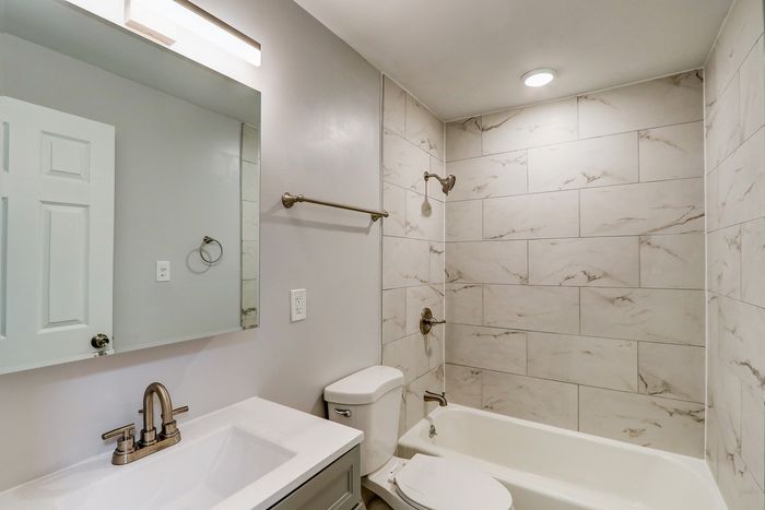 Modern bathroom featuring elegant marble-look tiles, sleek fixtures, and a spacious vanity.
