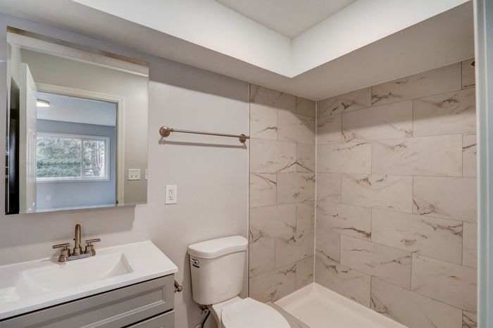Elegant bathroom with modern fixtures, featuring stylish marble-patterned tiles and a sleek white vanity.