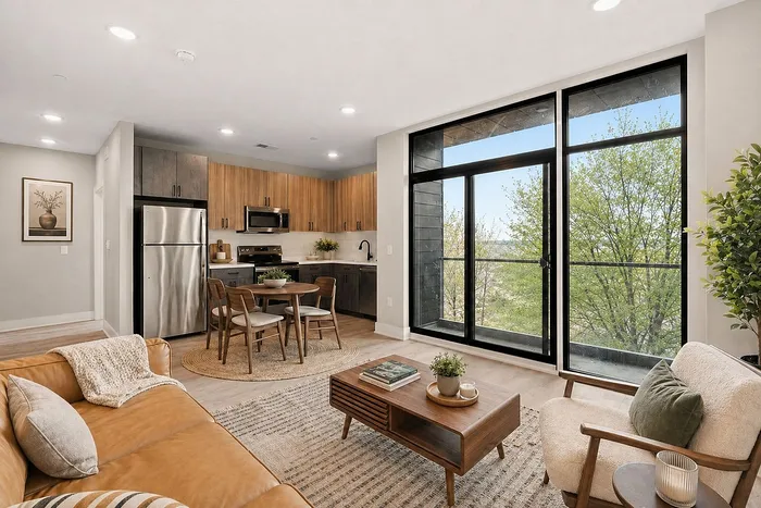 Contemporary open-concept living space with cozy seating, sleek kitchen, and floor-to-ceiling windows showcasing scenic views.