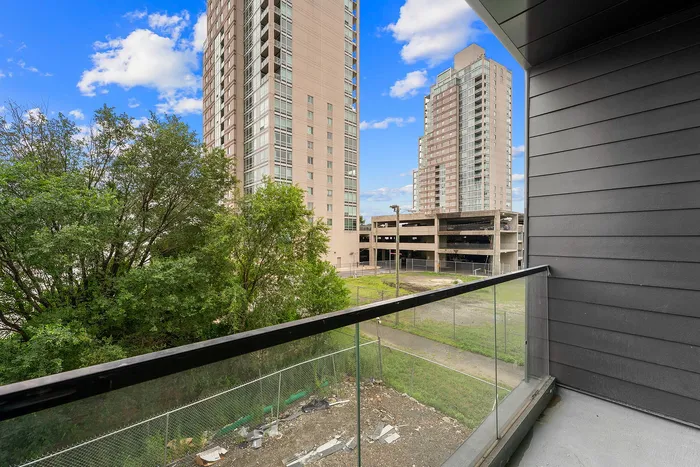 Chic balcony view showcasing modern high-rise buildings and lush greenery against a vibrant blue sky.