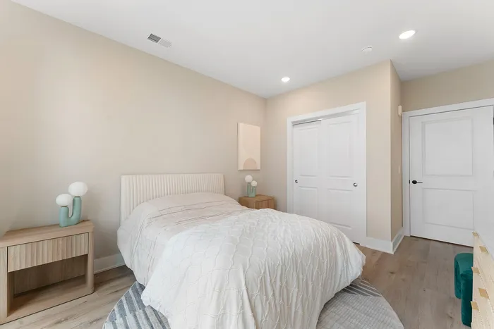 Elegant bedroom featuring soft beige walls, a cozy bed with plush white bedding, and stylish bedside tables with contemporary lamps.