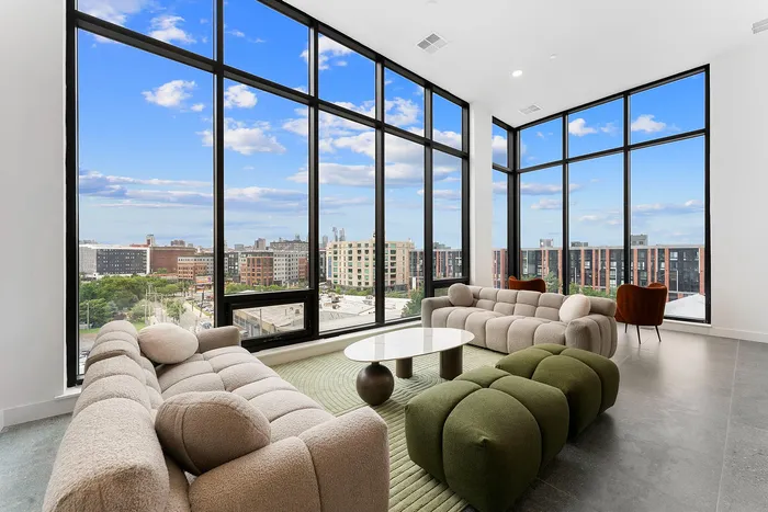 Luxurious living room with floor-to-ceiling windows offering a stunning urban view, elegant modern sofas, and stylish decor.