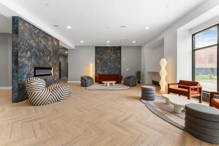 Modern lounge area with cozy seating, artistic lighting, and sleek fireplace, showcasing elegant hardwood flooring and abundant natural light.