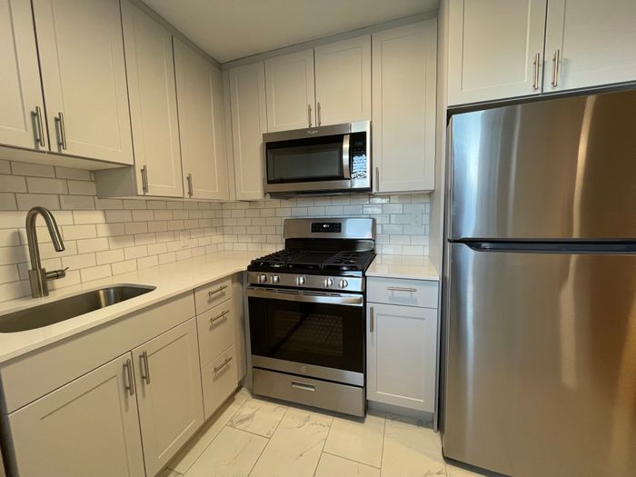 Modern kitchen with sleek stainless steel appliances, white cabinetry, and subway tile backsplash.