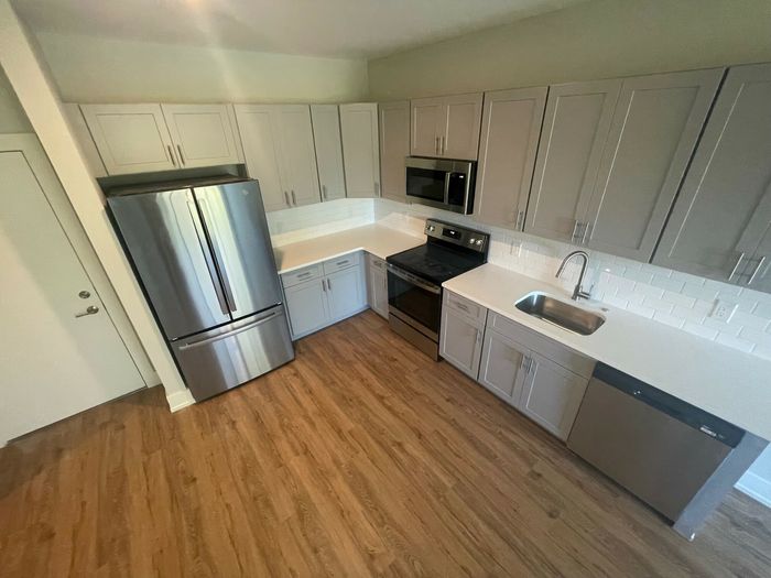 Modern kitchen with sleek stainless steel appliances, elegant cabinetry, and polished wooden flooring.