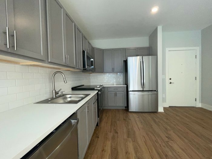 Modern kitchen with sleek gray cabinetry, stainless steel appliances, and elegant hardwood flooring.
