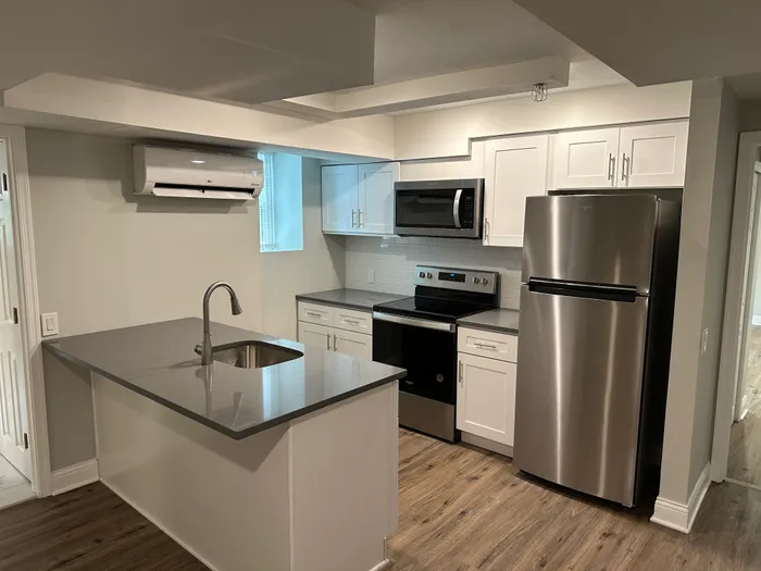 Modern kitchen with sleek gray countertops, stainless steel appliances, and elegant white cabinetry.