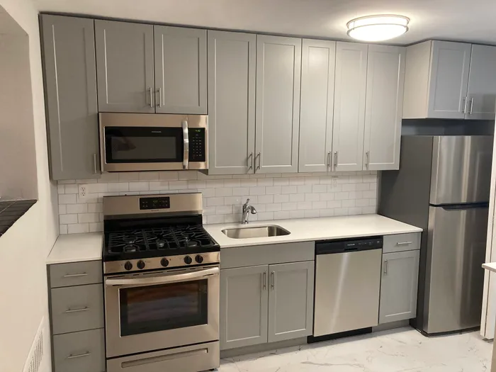 Modern kitchen with sleek gray cabinets, stainless steel appliances, and elegant subway tile backsplash.