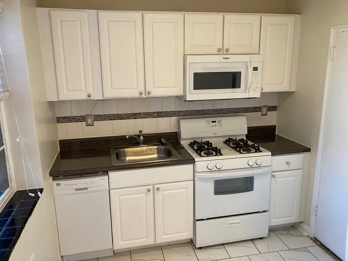 Charming kitchen with modern white cabinetry, sleek countertops, and integrated appliances, perfect for culinary adventures.